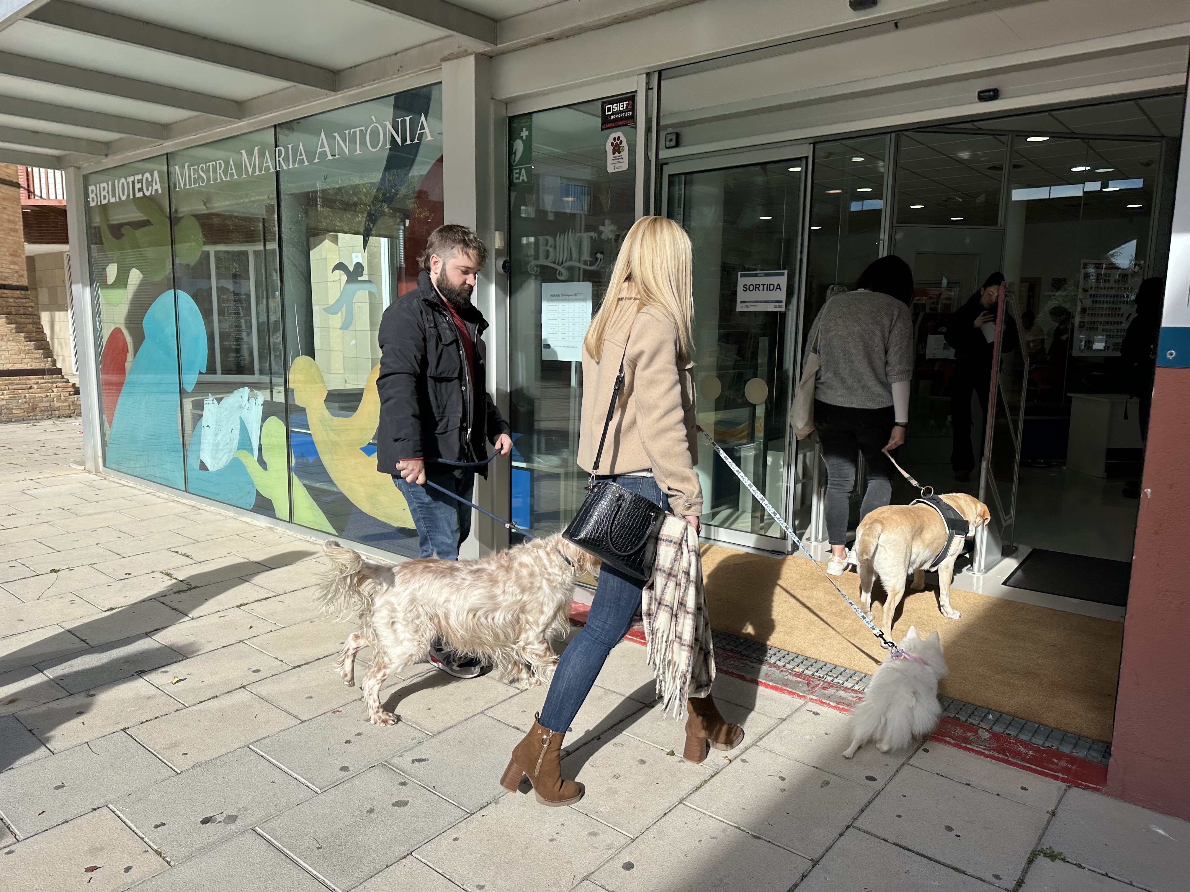 La Lila, la Julieta, l'Arya i els seus propietaris, accedint a la Biblioteca 