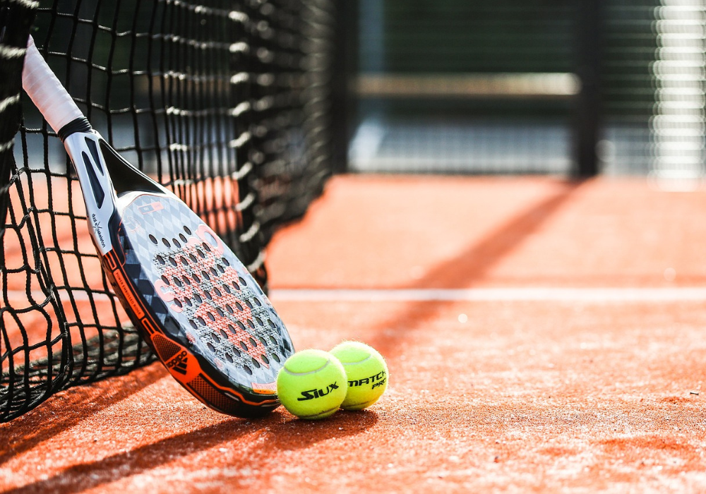 Foto d'una raqueta de pàdel amb dues pilotes a la pista