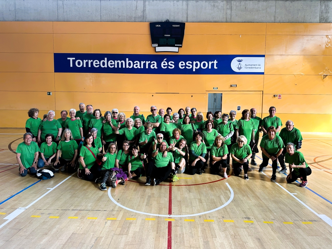 Un grup de persones participants a la gimnàstica per a la gent gran, amb les samarretes tècniques